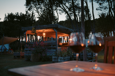 Atmosfera serale al Camping Ca Savio - Nordisk Village tenda Venezia con due bicchieri di vino sul tavolo.