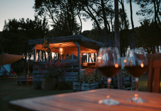 Vista al atardecer en Camping Ca Savio - Nordisk Village tienda Venecia con dos copas de vino en la mesa.