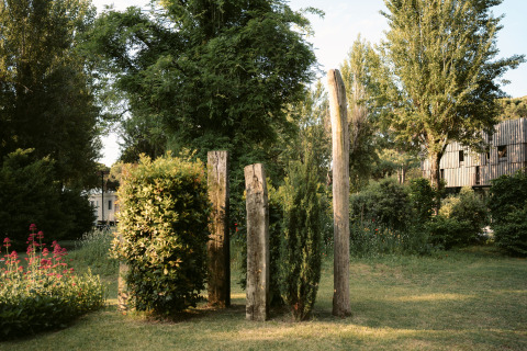 Nordisk Village Glamping bei Camping Ca Savio nahe Venedig mit Holzpfählen, Büschen und Bäumen im Grünen.