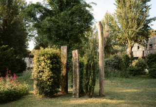 Glamping Nordisk Village al Camping Ca Savio vicino a Venezia con pali di legno, arbusti e alberi verdi.