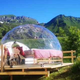 Glamping at Bubbelreis glass igloo in Isenthal, Switzerland, surrounded by green mountains and wildflowers.