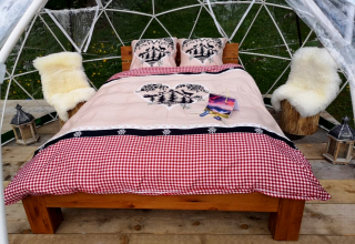 Glamping at Bubbelreis - Glazen Iglo Isenthal featuring a cozy bed, chairs, lanterns and dome tent outdoors.