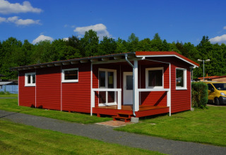 Cabane en bois rouge avec bordures blanches sur pelouse, Ferienanlage Erzeberg - Blockhütten Hessen camping.