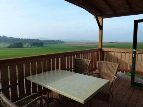 Vista desde una terraza con mesa y sillas en Ferienanlage Erzeberg - Blockhütten Hessen, experiencia glamping.