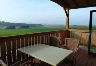 Vista desde una terraza con mesa y sillas en Ferienanlage Erzeberg - Blockhütten Hessen, experiencia glamping.