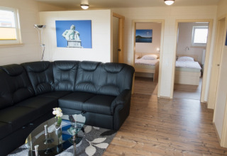 Interieur van Ferienanlage Erzeberg - Blockhütten Hessen met zwarte zetel en twee zichtbare slaapkamers.