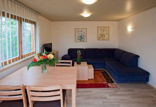 Woonruimte van glamping accommodatie bij Ferienanlage Erzeberg - Blockhütten Hessen met hoekbank en tafel.