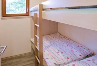 Et hyggeligt værelse i Ferienanlage Erzeberg - Blockhütten Hessen med køjeseng og vindue til naturen.