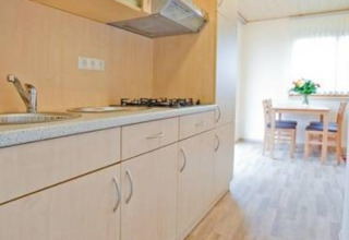 Moderne Küchenzeile in der Ferienanlage Erzeberg - Blockhütten Hessen mit Essbereich im Hintergrund.