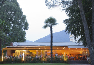 Udendørs restaurant på Campofelice Camping Village - Igloo Tube Lago Maggiore omgivet af træer og bjerge