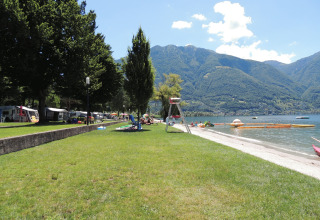 Udsigt over Campofelice Camping Village ved Lago Maggiore med grønne områder, sø og bjerge i baggrunden.