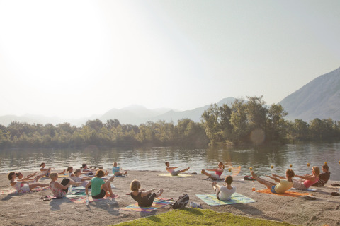 Personas haciendo yoga en grupo sobre esterillas junto al lago, en Campofelice Camping Village, Lago Maggiore.