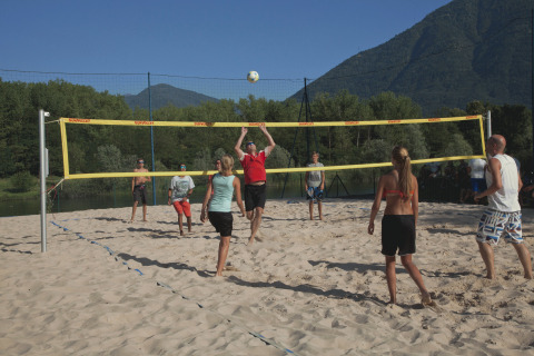 Mensen spelen beachvolley op zand bij Campofelice Camping Village – Igloo Tube Lago Maggiore in de zon.