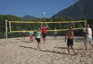 Folk spiller beachvolley på sand ved Campofelice Camping Village – Igloo Tube Lago Maggiore i solskin.