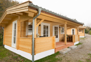Wooden glamping cabin at Campingpark Wiesenbeker Teich with porch, set in a peaceful natural environment.