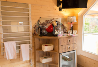 Interni di sistemazione glamping con macchina da caffè, minibar, scaffali in legno e illuminazione calda.