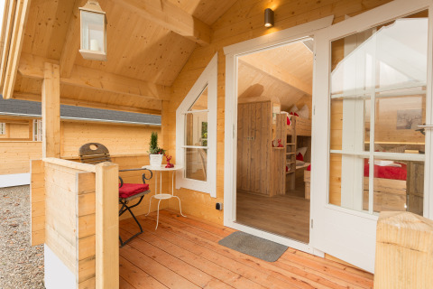Terrazza in legno e interno accogliente di una cabina glamping al Campingpark Wiesenbeker Teich.