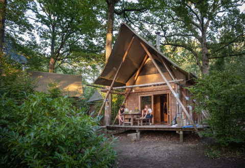 Glamping-Unterkunft im Grünen bei Huttopia Rambouillet - Glamping île de France, zwei Personen auf der Terrasse.