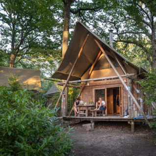 Glampingverblijf bij Huttopia Rambouillet - Glamping île de France, twee personen ontspannen buiten op het terras.