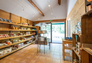 Winkel met schappen vol lokale producten bij Huttopia Rambouillet Glamping, Île-de-France, nabij de uitgang.