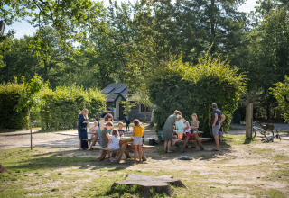Des familles réunies autour de tables de pique-nique à Huttopia Rambouillet - Glamping île de France.