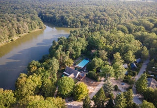 Luftaufnahme von Huttopia Rambouillet - Glamping île de France, umgeben von Wald, See und Hütten.