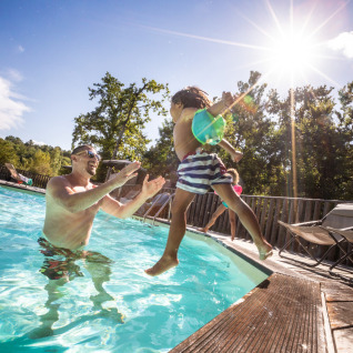 Familie genießt das Schwimmen im Pool von Huttopia Caminos de Galicia - Glamping Galicië bei Sonnenschein.