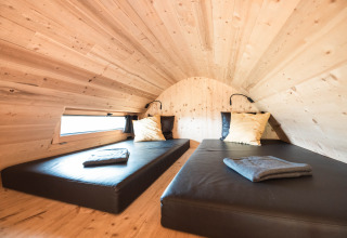 Interior view of a luxury wooden glamping chalet with two beds at Alpencamping Nenzing in Vorarlberg.