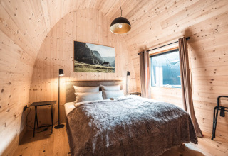 Luxe chalet op Alpencamping Nenzing in Vorarlberg met houten wanden, tweepersoonsbed en groot raam.