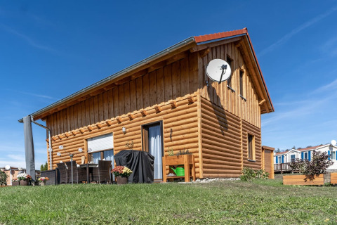 Wooden lodge at Camping & Vakantiepark Orsingen - Landhuis Baden-Württemberg on a sunny, clear day.