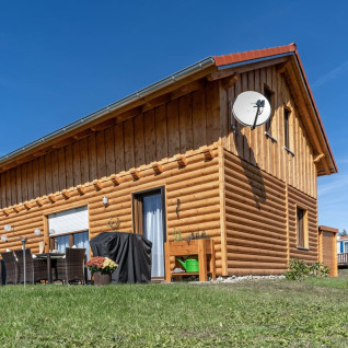Wooden lodge at Camping & Vakantiepark Orsingen - Landhuis Baden-Württemberg on a sunny, clear day.