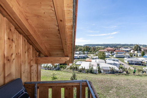 Vista desde un balcón de madera hacia Camping & Vakantiepark Orsingen, Landhuis Baden-Württemberg, en un día soleado.