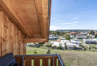 Vista desde un balcón de madera hacia Camping & Vakantiepark Orsingen, Landhuis Baden-Württemberg, en un día soleado.