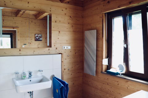 Badeværelse i træhytte på Camping & Vakantiepark Orsingen - Landhuis Baden-Württemberg, med vask og vindue.