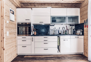Modern, fully equipped wooden kitchen in glamping accommodation at Camping & Vakantiepark Orsingen, Baden-Württemberg.