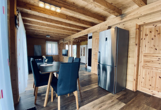 Moderne glamping-indkvartering med træinteriør, spisebord og køkken i Camping & Vakantiepark Orsingen.