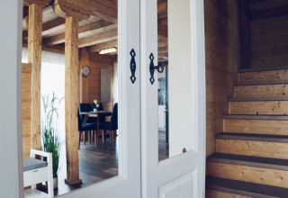 Interieur van een gezellig houten glampinghuis met trap, eetruimte en veel daglicht in Orsingen.