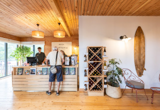 Reception with wooden decor, wine rack, guest checking in at Camping Huttopia Arcachon glamping.