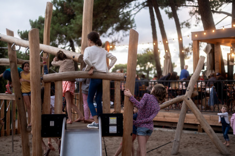Kinderen spelen op een houten speeltuin bij Camping Huttopia Arcachon - Glamping Nouvelle-Aquitaine in het bos.