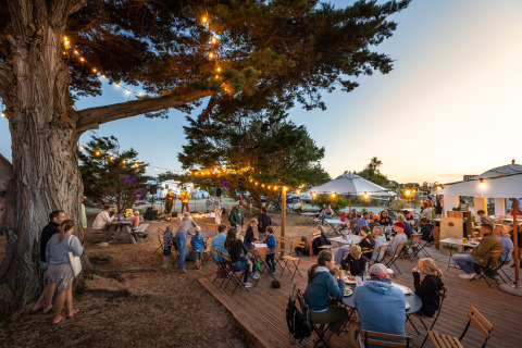 Sera al glamping Huttopia Ars-en-Ré Nouvelle-Aquitaine con persone, luci e alberi in un ambiente rilassato.