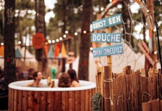 Glamping site in the woods with a jacuzzi, Dutch sign, and tents at Forestcamp Biscarrosse.