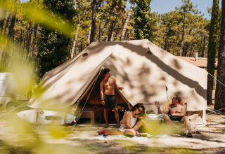 Drie mensen ontspannen voor een glamping tent bij Forestcamp Biscarrosse, omringd door bomen en zonlicht.