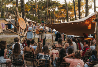 Buitenoptreden met muziek tussen tenten en bomen bij glamping 'Enter the Wave – Forestcamp Biscarrosse'.
