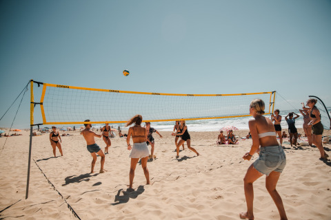 Persone giocano a beach volley sotto il sole al glamping Enter the wave – Forestcamp Biscarrosse sulla spiaggia.