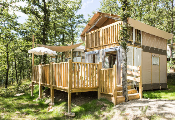 To-etagers glamping-indkvartering på Vallicella Glamping Resort i Toscana, omgivet af grønne træer.
