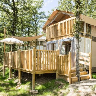 Alojamiento glamping de dos pisos en Vallicella Glamping Resort en Toscana, rodeado de árboles verdes.