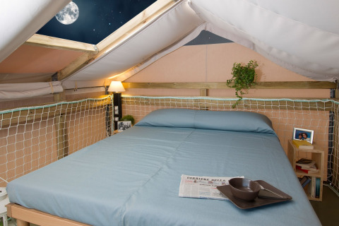 Cozy glamping accommodation with bed and skylight overlooking the moon at Vallicella Glamping Resort, Tuscany.