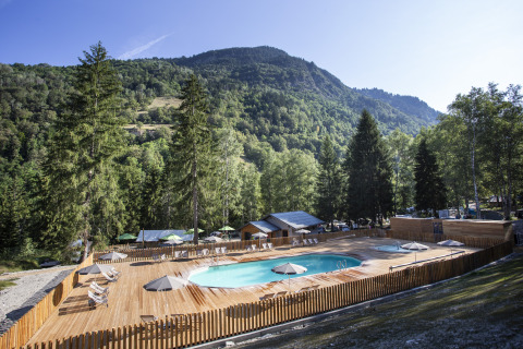 Træterrasse med swimmingpool og liggestole i de naturskønne bjerge ved Huttopia Vanoise – Bozel, Glamping Savoie.