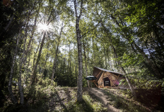 Glampingindkvartering Huttopia Vanoise – Bozel i Savoie, Frankrig, omgivet af frodig skov og sollys.
