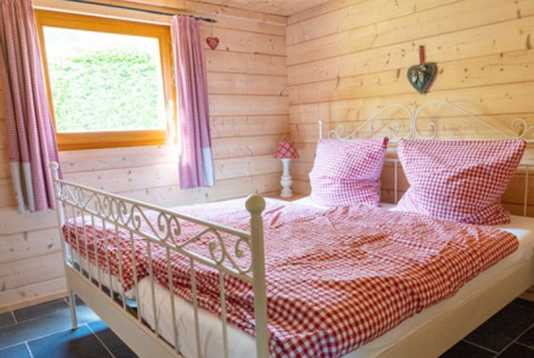 Chambre confortable avec literie à carreaux rouges au Natur-Camping Langenwald, glamping en Bade-Wurtemberg.